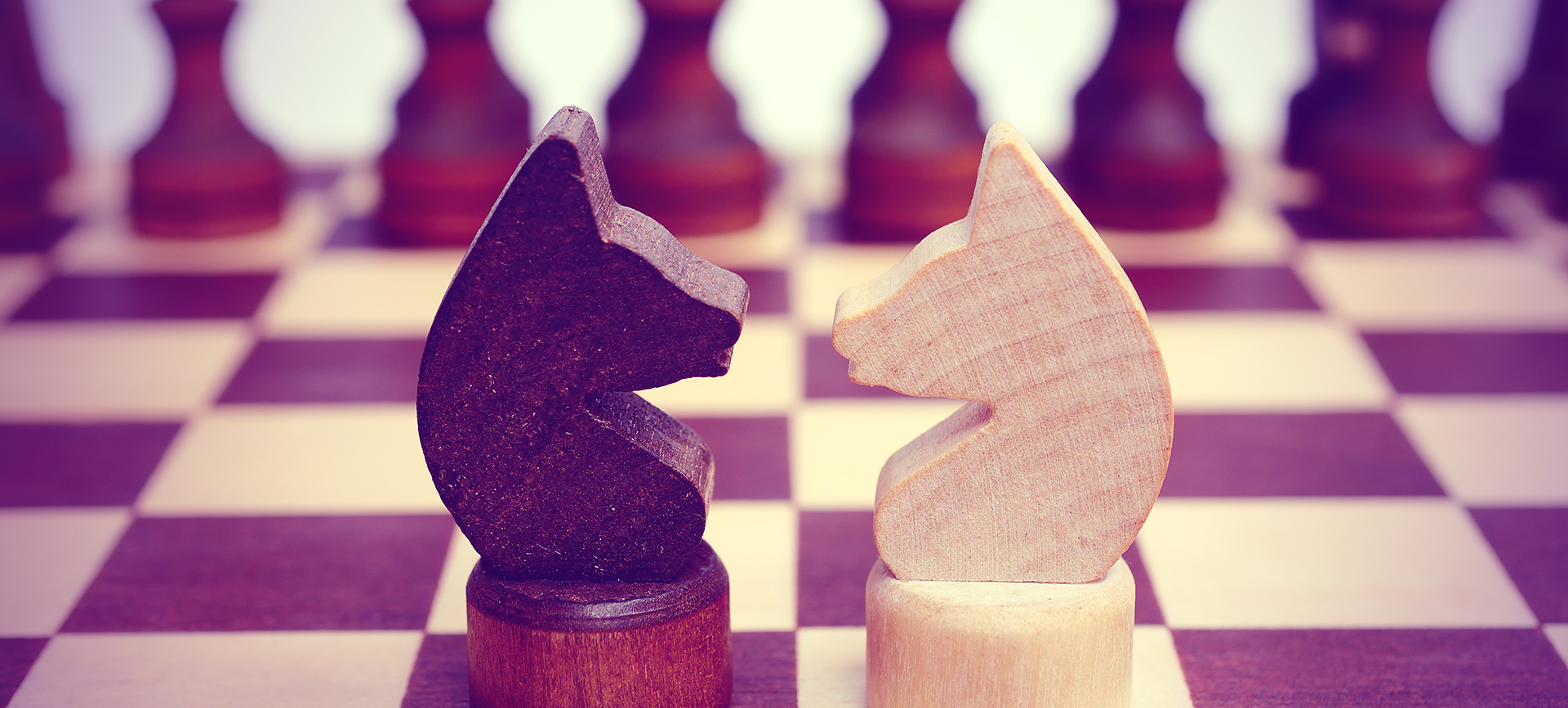 Two knight on a chessboard. Light and dark. Confrontation. Against each other. Forehead to forehead. Vintage toning.